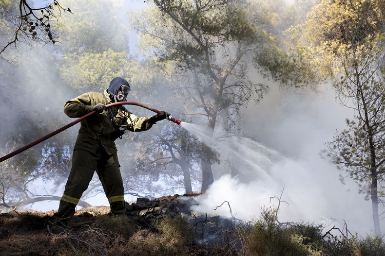 Un bombero intenta sofocar las llamas en el área de Keratea, al sureste de Atenas, Grecia, el domingo 30 de junio de 2024. (AP Foto/Yorgos Karahalis)