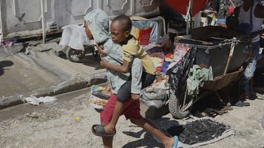 Un joven carga a un niño sobre su espalda en una escuela que actualmente sirve como albergue para quienes huyen de la violencia de las pandillas, el lunes 14 de abril de 2025, en Puerto Príncipe, Haití. (AP Foto/Odelyn Joseph)