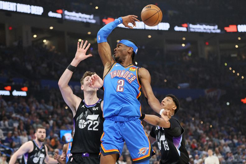 Shai Gilgeous-Alexander (2), del Thunder de Oklahoma City, pasa el balón sobre Kyle Filipowski (22) y Ace Bailey (19), del Jazz de Utah, durante la primera mitad del juego de baloncesto de la NBA, el domingo 5 de abril de 2026, en Oklahoma City. (AP Foto/Nate Billings)