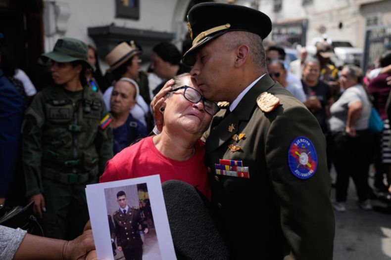 Un oficial militar consuela a Ramona Palma --madre del soldado venezolano César García, quien murió durante una redada estadounidense en la que fue capturado el presidente venezolano Nicolás Maduro-- después del velorio de García, el miércoles 7 de enero de 2026, en Caracas, Venezuela. (AP Foto/Matías Delacroix)