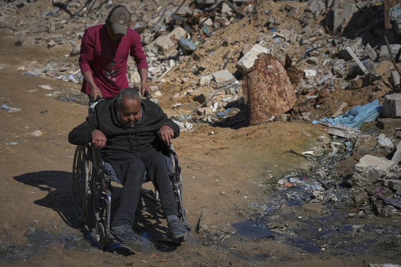 Wasem Attiya empuja a su padre, Mohamed, de 54 años, en una silla de ruedas mientras se dirigen al hospital Shifa en la ciudad de Gaza para una sesión de diálisis, el lunes 14 de abril de 2025. (AP Foto/Jehad Alshrafi)