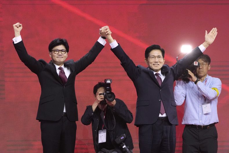 El exlíder del Partido del Poder del Pueblo Han Dong-hun (izquierda), y el exministro de Trabajo de Corea del Sur Kim Moon Soo saludan con los brazos en alto durante una convención de la formación en Goyang, Corea del Sur, el 3 de mayo de 2025. (AP Foto/Ahn Young-joon)