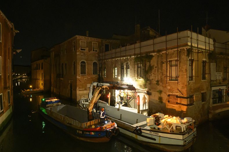 En esta imagen disponible el jueves 24 de julio de 2025, la obra de Banksy The Migrant Child es retirada de la fachada del Palazzo San Pantalon en Venecia, Italia, para completar su restauración. (Ifis Art Via AP)