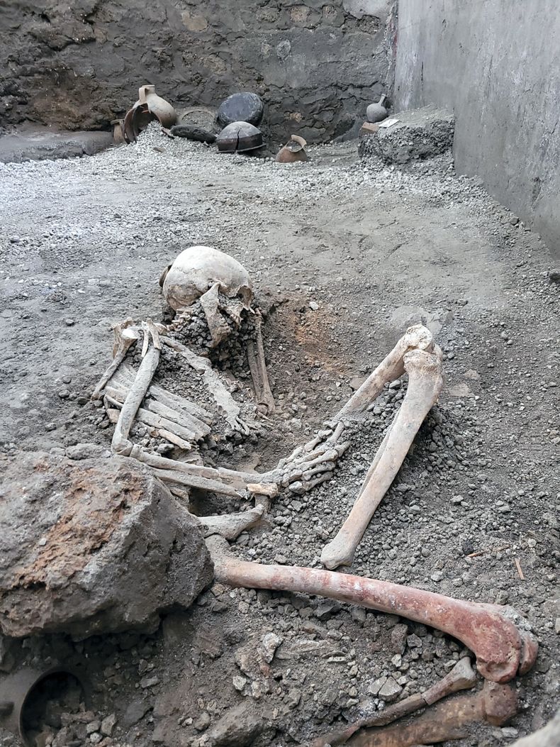 Fotografía proporcionada el martes 16 de mayo de 2023 por la oficina de prensa de la zona arqueológica de Pompeya que muestra uno de dos esqueletos descubiertos que los arqueólogos creen que fueron de unos hombres que murieron cuando un muro se derrumbó sobre ellos durante los poderosos terremotos que acompañaron la erupción del monte Vesubio que destruyó la antigua ciudad de Pompeya en el año 79 de Nuestra Era. (Zona Arqueológica de Pompeya vía AP)