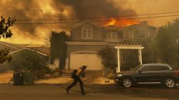 Una residencia en llamas mientras un bombero combate un incendio en Pacific Palisades, el martes 7 de enero de 2025, en Los Ángeles. (AP Foto/Eugene Garcia)