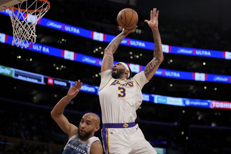 Anthony Davis (3), de los Lakers de Los Ángeles, se alza para anotar superando a Jordan McLaughlin, de los Timberwolves de Minnesota, durante la primera mitad del juego de baloncesto de la NBA, el domingo 10 de marzo de 2024. (AP Foto/Eric Thayer)