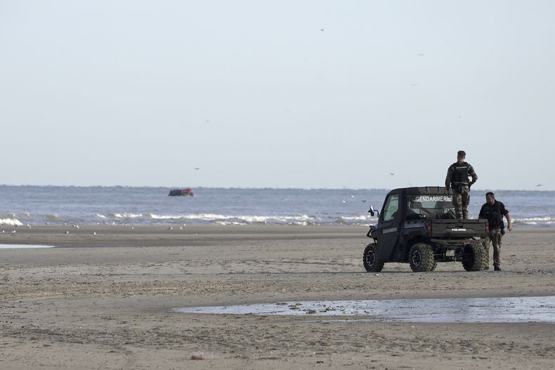 Gendarmes observan una pequeña embarcación con migrantes desde la playa de Ecault, en Francia, el 4 de julio de 2025.