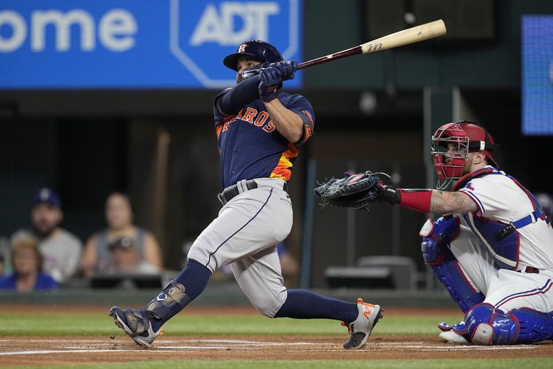 Houston Astros Jose Altuve, left, follows through on a solo home run as Texas Rangers Jonah Heim looks on in the first inning of a baseball game, Tuesday, Sept. 5, 2023, in Arlington, Texas. (AP Photo/Tony Gutierrez)