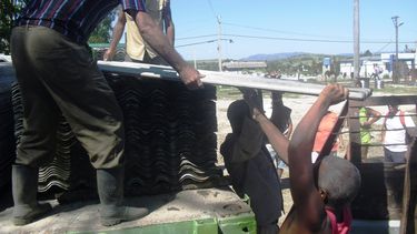 Damnificados por el paso del huracán Sandy reciben tejas para techar sus viviendas.