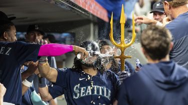 El dominicano de los Marineros de Seattle Julio Rodriguez le lanza agua al venezolano Eugenio Suárez tras conectar un jonrón de dos carreras frente al relevista de Oliver Ortega de los Mellizos de Minnesota en el encuentro del lunes 17 de julio del 2023. (AP Foto/Stephen Brashear)