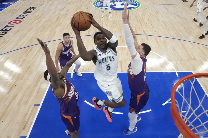 Anthony Edwards, base de los Timberwolves de Minnesota, se eleva para disparar frente a Bradley Beal (izquierda) y Jusuf Nurkic, de los Suns de Phoenis, en el segundo partido de la serie de primera ronda de playoffs, disputado el martes 23 de abril de 2024 (AP Foto/Abbie Parr)