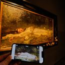 En el celular, el video de la canción The Fate of Ophelia de Taylor Swift, y al fondo, el cuadro en que se inspiró, obra de Friedrich Heyser, en un museo en Wiesbaden, Alemania, el 16 de octubre del 2025. (AP foto/Michael Probst)