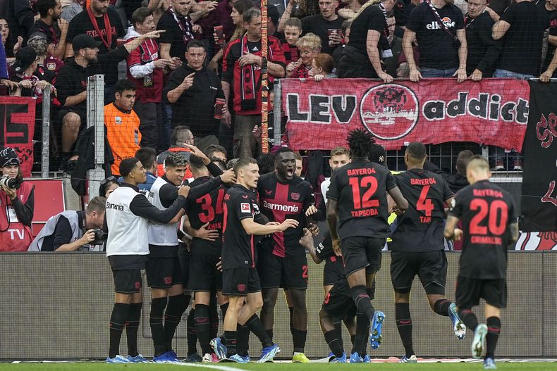 Victor Boniface (centro) celebra junto a sus compañeros del Bayer Leverkusen luego del tercer gol de su equipo ante el Colonia en partido de la Liga Alemana en el BayArena en Leverkusen, Alemania, el domingo 8 de octubre de 2023. (AP Foto/Martin Meissner)