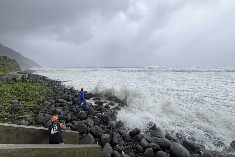 Gente mirando mientras las fuertes olas golpeando la costa en Basco, provincia de Batanes, en el norte de Filipinas, mientras el tifón Ragasa afecta a la zona el lunes 22 de septiembre de 2025. (AP Foto/Justine Mark Pillie Fajardo)