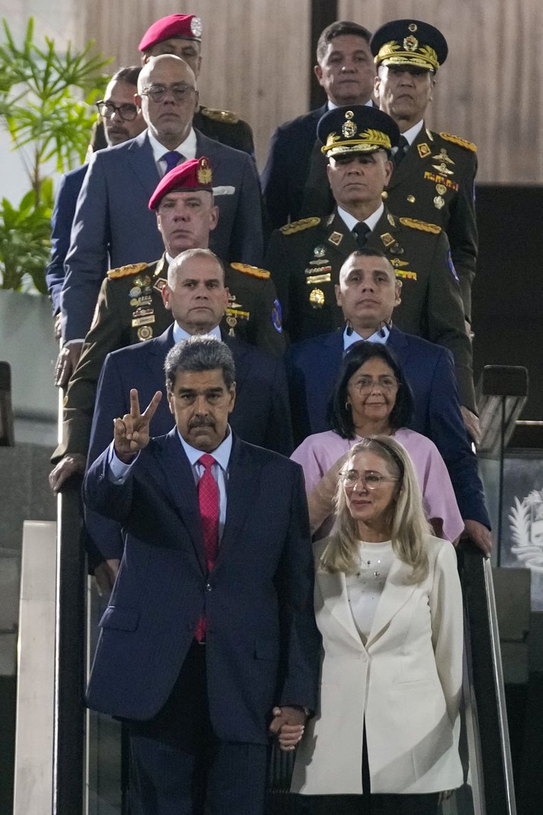 El presidente venezolano, Nicolás Maduro, hace un gesto de victoria mientras agarra de la mano a su esposa Cilia Flores en el Tribunal Supremo en Caracas, Venezuela, el miércoles 31 de julio de 2024, tres días después de las elecciones en las que fue declarado ganador. A la derecha, segundo desde abajo, la vicepresidenta Delcy Rodríguez. A la izquierda, arriba del todo, el presidente de la Asamblea Nacional, Jorge Rodríguez. (AP Foto/Fernando Vergara)