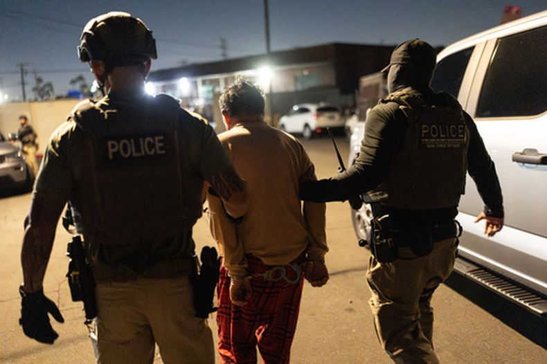 Agentes de un equipo de Investigaciones de Seguridad Nacional llevan a un sospechoso de registrarse de forma ilegal para votar durante una operación federal en Commerce, California, el lunes 19 de octubre de 2026. (AP Foto/Jae C. Hong)