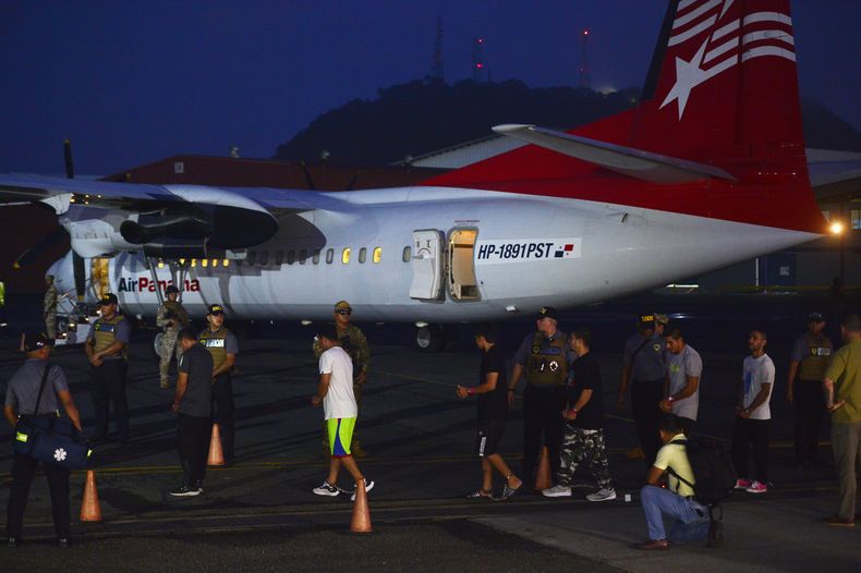 Migrantes colombianos caminan esposados y con grilletes hacia un avión para ser deportados en el aeropuerto Marcos A. Gelabert de Albrook en la Ciudad de Panamá, el martes 20 de agosto de 2024. (AP Foto/Agustín Herrera)