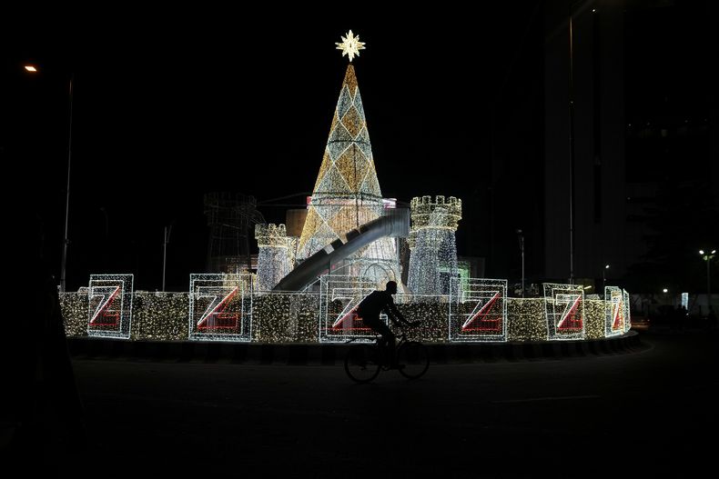 Un hombre monta una bicicleta frente a decoraciones de Navidad en una calle de Lagos, Nigeria, el viernes 20 de diciembre de 2024. (AP Foto/Sunday Alamba)