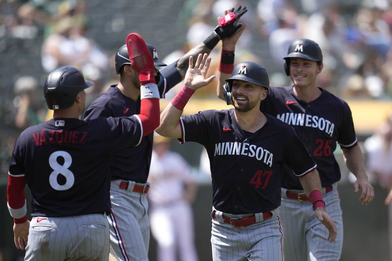 El puertorriqueño Christian Vazquez felicita a Edouard Julien y Max Kepler después de que ambos anotaron con un doble de Alex Kirilloff en la séptima entrada del juego ante los Atléticos de Oakland el domingo 16 de julio del 2023. (AP Foto/Jeff Chiu)