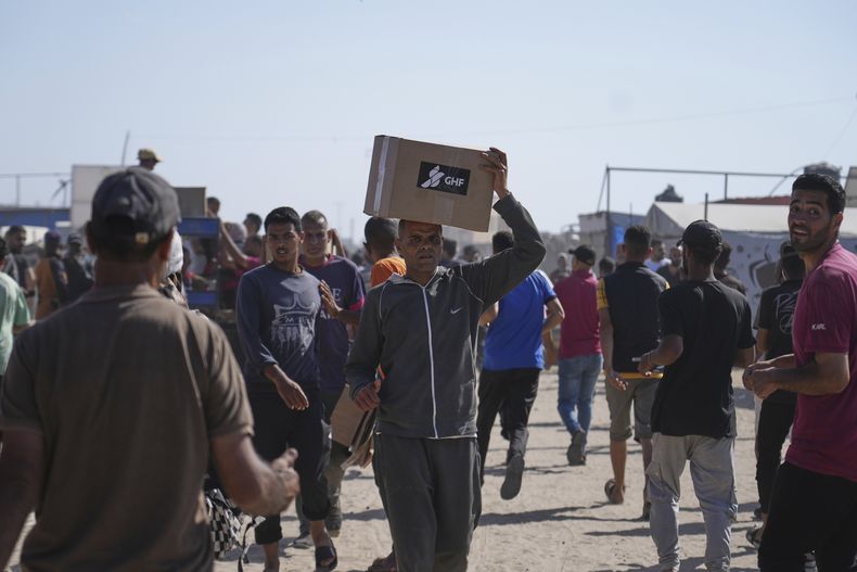 Palestinos llevan cajas que contienen alimentos y paquetes de ayuda humanitaria entregados por la Fundación Humanitaria de Gaza, una organización respaldada por Estados Unidos y aprobada por Israel, en Rafah, en el sur de la Franja de Gaza, el martes 27 de mayo de 2025. (AP Foto/Abdel Kareem Hana)