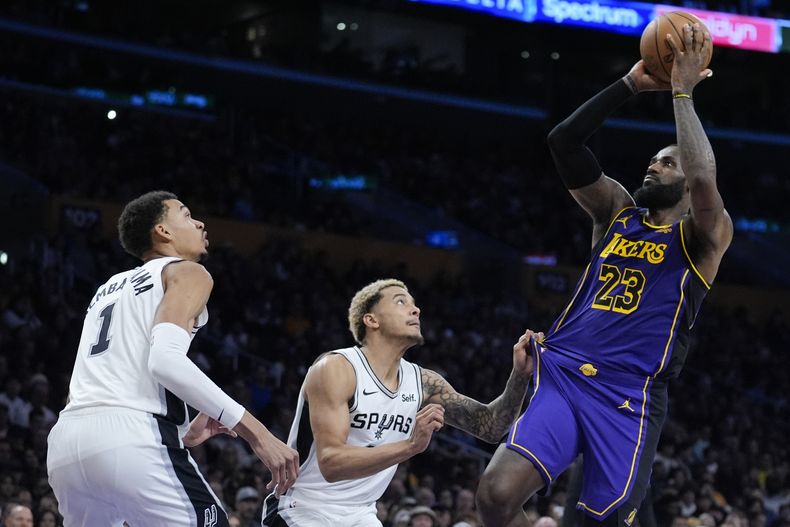 LeBron James, de los Lakers de Los Ángeles, encesta frente a Jemmy Sochan (centro) y Victor Wembanyama, de los Spurs de San Antonio, el viernes 23 de febrero de 2024 (AP Foto/Marcio José Sánchez)