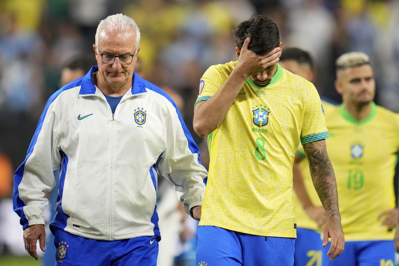 El entrenador de la selección de Brasil, Dorival Júnior, izquierda, camina al lado de Lucas Paqueta (8) y sus compañeros después de perder en serie de penaltis contra Uruguay durante los cuartos de final de la Copa América, en Las Vegas, el sábado 6 de julio de 2024. (AP Foto/Julio Cortez)