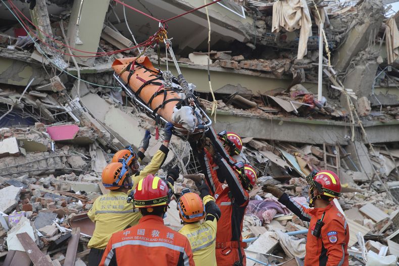 En esta imagen publicada por la Agencia de Noticias Xinhua, miembros de un equipo chino de búsqueda y rescate traslada a una sobreviviente embarazada desde un edificio derruido tras un sismo en Mandalay, Myanmar, el lunes 31 de marzo de 2025. (Myo Kyaw Soe/Xinhua via AP)