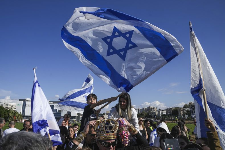 Varias personas se congregan mientras esperan por la llegada de cuatro soldados israelíes que fueron liberadas por Hamás, junto al helipuerto del Hospital Beilinson en Petaj Tikva, cerca de Tel Aviv, Israel, el sábado 25 de enero de 2025. (AP Foto/Maya Alleruzzo)