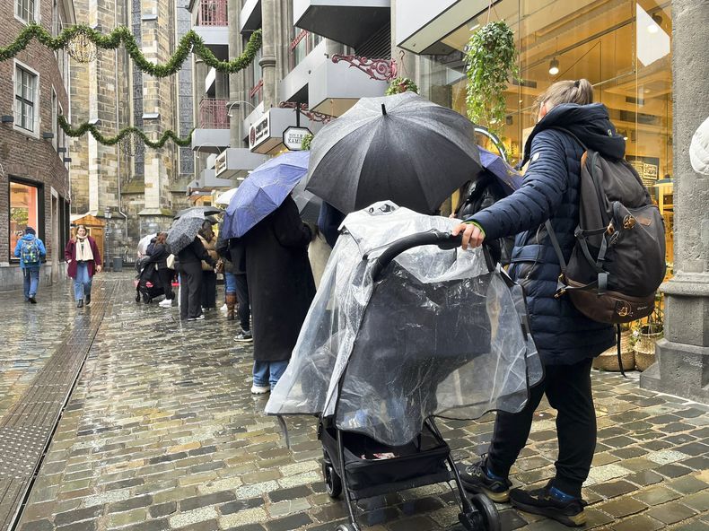 Personas hacen fila fuera de la chocolatería Lindt para comprar una edición limitada de Chocolate Dubái, el jueves 14 de noviembre de 2024, en Aachen, Alemania. (AP Foto/Daniel Niemann)