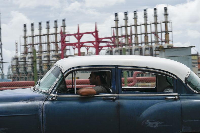 Una persona conduce un automóvil clásico estadounidense junto a un generador flotante que no produce electricidad desde hace días en La Habana, Cuba, el viernes 18 de octubre de 2024. (AP Foto/Ramón Espinosa)