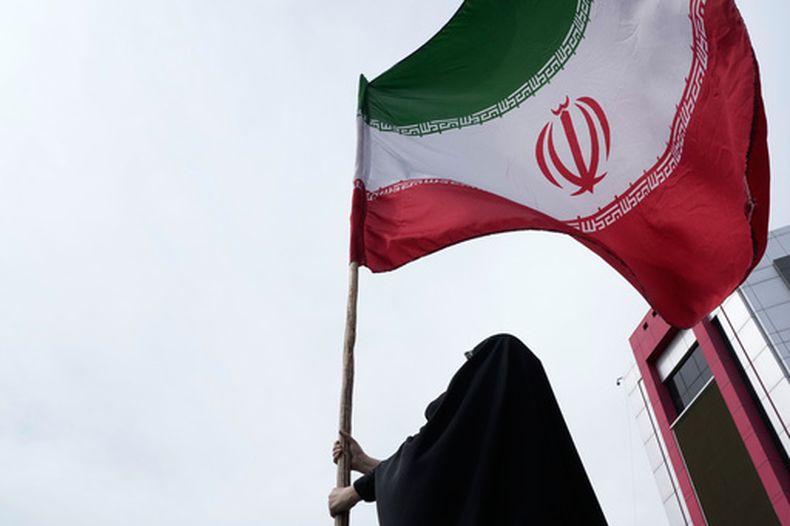 Una mujer sostiene una bandera iraní para una campaña progobierno en el centro de Teherán, Irán, el sábado 25 de abril de 2026. (AP Foto/Vahid Salemi)