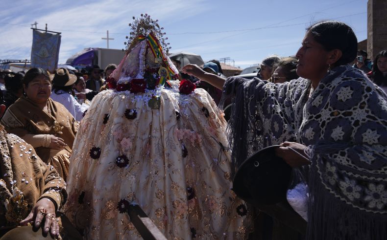 Una devota extiende la mano para tocar a la pequeña Virgen María de las Letanías durante una procesión en su honor en la cima de una montaña cerca de su santuario, en las afueras de Viacha, Bolivia, el sábado 13 de julio de 2024. (Foto AP/Juan Karita)