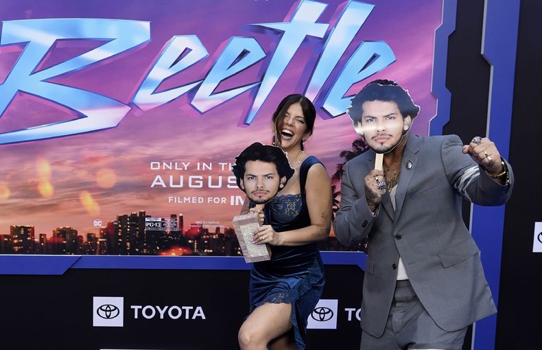 Ángel Manuel Soto, derecha, director de la película Blue Beetle, y su esposa Carla González, con máscaras del astro de la película Xolo Maridueña en una función de la película el 15 de agosto de 2023, en el Teatro Chino TCL en Los Angeles. Maridueña no pudo asistir a la premiere por la huelga de actores de Hollywood. (Foto AP/Chris Pizzello)