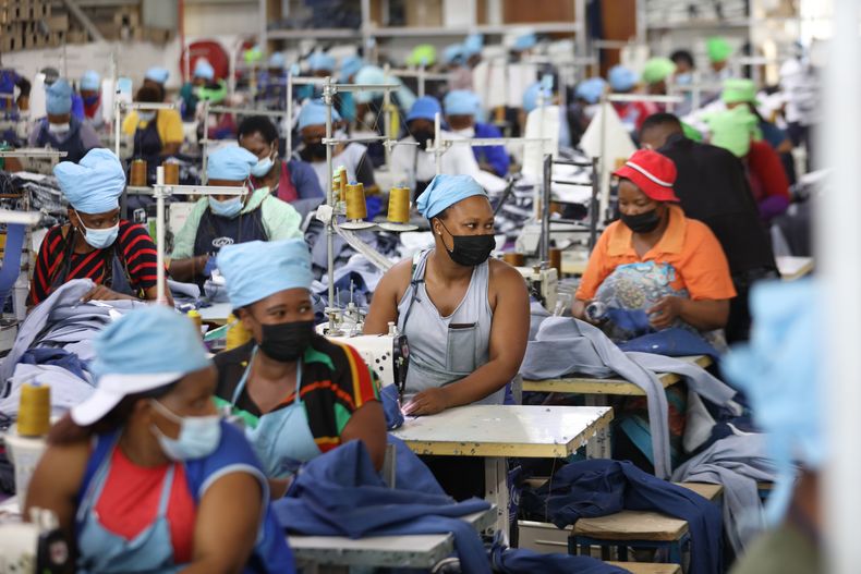 ARCHIVO - Matumelo Manosa, centro, trabaja en una fábrica textil en Maseru, Lesoto, el jueves 24 de febrero de 2022. (AP Foto/Neo Ntsoma, Archivo)