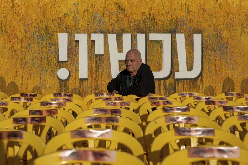Luis Har, rescatado de su cautiverio impuesto por Hamás en una incursión israelí el año pasado, posa para una foto, rodeado de sillas vacías con fotografías de los ojos de otros rehenes, en Tel Aviv, Israel, el lunes 6 de enero de 2025. (AP Foto/Ohad Zwigenberg)