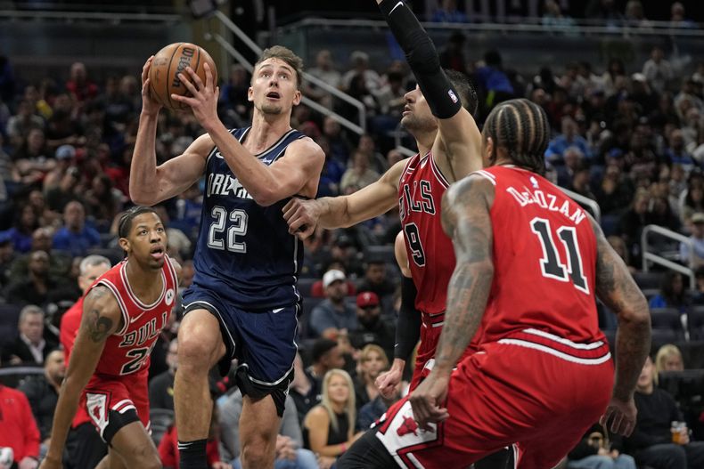 El alero del Magic de Orlando Franz Wagner (22) tira frente al alero de los Bulls de Chicago Dalen Terry, a la izquierda, al pívot Nikola Vucevic (9) y al alero DeMar DeRozan (11) durante la primera mitad del partido de baloncesto de la NBA, el sábado 10 de febrero de 2024, en Orlando, Florida (AP Foto/John Raoux)