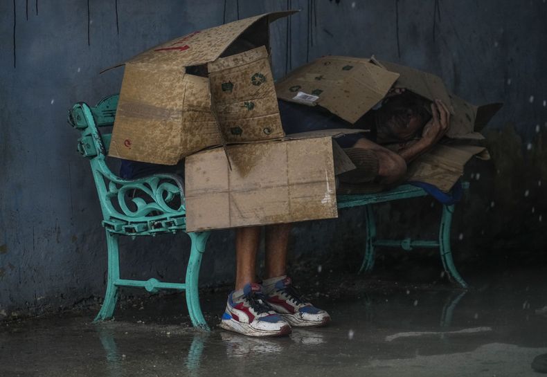 Personas en una parada de autobús se protegen con cartones del viento y la lluvia durante el paso del huracán Rafael en La Habana, Cuba, el miércoles 6 de noviembre de 2024. Tras su paso, la isla buscaba recuperarse; un apagón nacional provocado por el huracán se mantiene en gran parte del país el 7 de noviembre de 2024. (Foto AP/Ramón Espinosa)