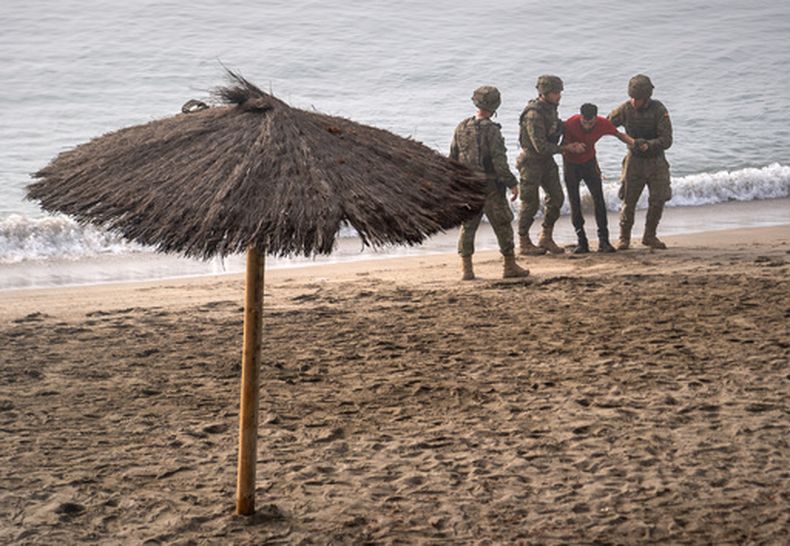 Soldados del ejército español ayudan a una persona que llegó a nado al enclave español de Ceuta, en el norte de África, desde Marruecos, el 1 de agosto de 2026. (AP Foto/Antonio Sempere)
