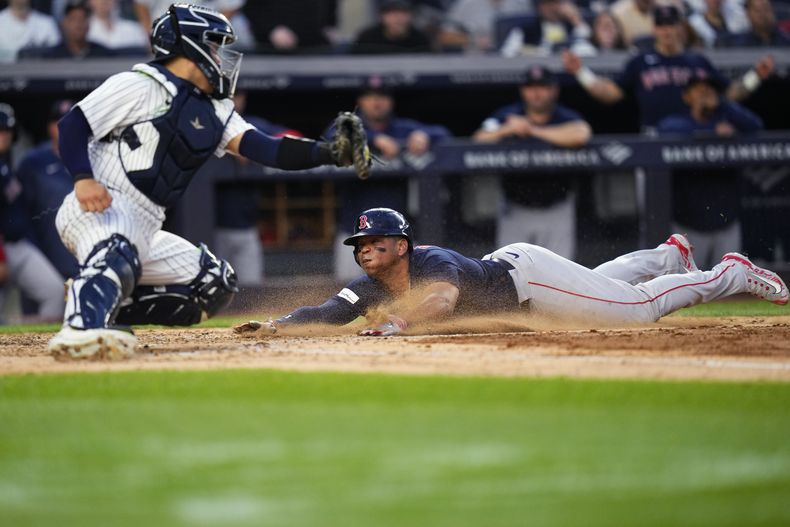 El dominicano Rafael Devers, de los Medias Rojas de Boston, se desliza frente al catcher José Trevino de los Yanquis de Nueva York, en el juego del viernes 9 de junio de 2023 (AP Foto/Frank Franklin II)