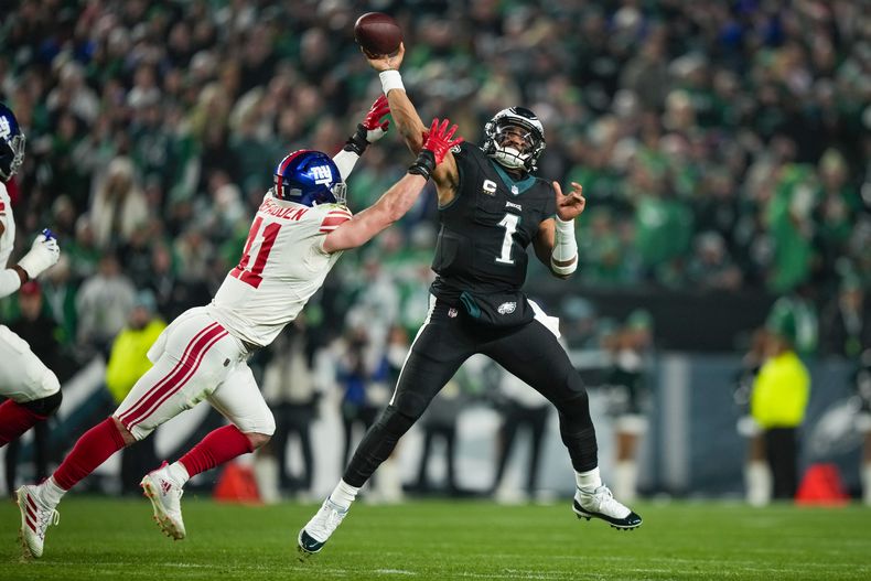 El quarterback de los Eagles de Filadelfia Jalen Hurts lanza el balón bajo presión del linebacker de los Giants de Nueva York Micah McFadden en el encuentro del lunes 25 de diciembre del 2023. (AP Foto/Matt Slocum)