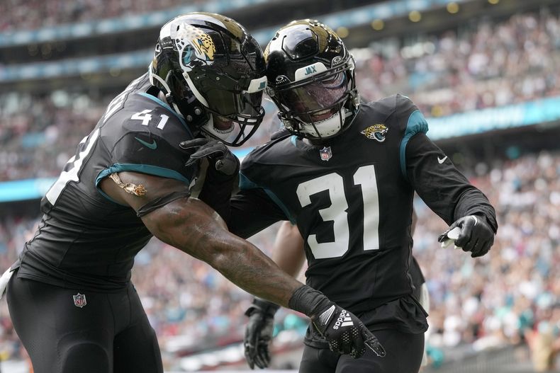 El cornerback Darious Williams (31) celebra con el linebacker Josh Allen (41) tras anotar un touchdown para los Jaguars de Jacksonville en la victoria ante los Falcons de Atlanta, el domingo 1 de octubre de 2023, en Londres. (AP Foto/Kirsty Wigglesworth)