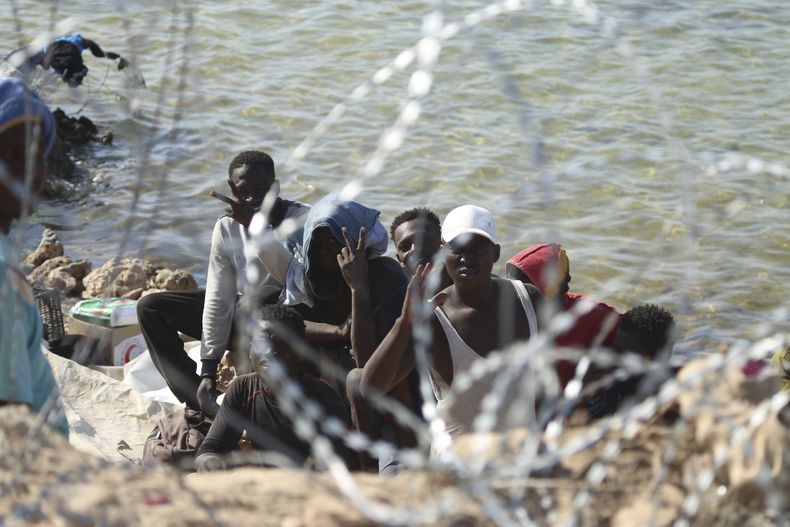 Migrantes se reúnen en una zona cerca de la frontera entre Libia y Túnez, mientras las fuerzas de seguridad libias y los trabajadores de la Cruz Roja libia les entregan alimentos, el domingo 23 de julio de 2023. (AP Foto/Yousef Murad, Archivo)