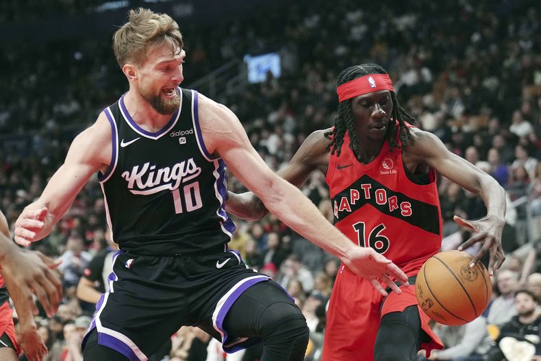 El ala-pívot de los Kings de Sacramento Domantas Sabonis (10) y el alero de los Raptors de Toronto Mouhamadou Gueye (16) disputan el balón durante la segunda mitad del juego de baloncesto de la NBA, en Toronto, el miércoles 20 de marzo de 2024. (Nathan Denette/The Canadian Press via AP)