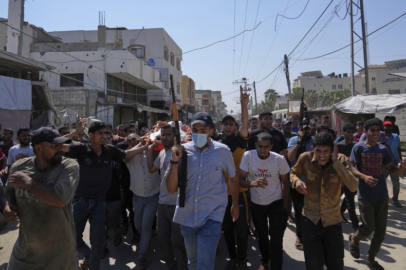 Palestinos, algunos de ellos armados, trasladan el cuerpo de Farouq Khattab, de 29 años, que murió en un ataque del ejército israelí en la Franja de Gaza, durante su funeral en Deir al-Balah, el 2 de julio de 2025. (AP Foto/Abdel Kareem Hana)