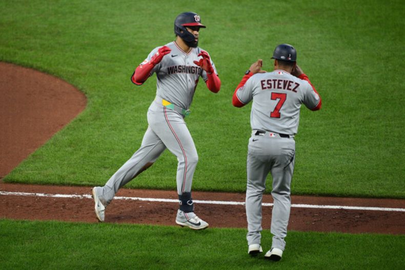 Luis Garcia Jr., izquierda, de los Nacionales de Washington, celebra con el coach de tercera base, Victor Estevez (7), mientras recorre las bases después de batear un jonrón durante la quinta entrada del juego de béisbol de Grandes Ligas contra los Orioles de Baltimore, el sábado 27 de junio de 2026, en Baltimore. (AP Foto/Nick Wass)