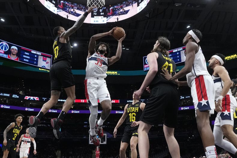 El alero de los Wizards de Washington, Marvin Bagley III (35), busca disparar bajo la presión del alero del Jazz de Utah, John Collins, arriba a la izquierda, durante la segunda mitad de un partido de baloncesto de la NBA, el jueves 25 de enero de 2024, en Washington. (AP Foto/Mark Schiefelbein)