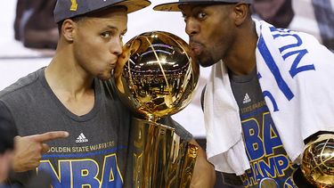 ARCHIVO- Stephen Curry, izquierda, y Andre Iguodala, de los Warriors de Golden State besan el trofeo Larry OBrien después de derrotar a los Cavaliers de Cleveland 105-97 en el Juego 6 de las Finales de la NBA en Cleveland, el 17 de junio de 2015. Iguodala, cuatro veces campeón de la NBA con los Warriors de Golden State durante 19 años de carrera, se retira.(AP Foto/Paul Sancya, Archivo)