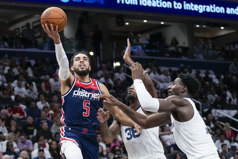Tyus Jones, base de los Wizards de Washington, salta hacia el aro junto a Marcus Smart, de los Grizzlies de Memphis, el sábado 28 de octubre de 2023 (AP Foto/Alex Brandon)