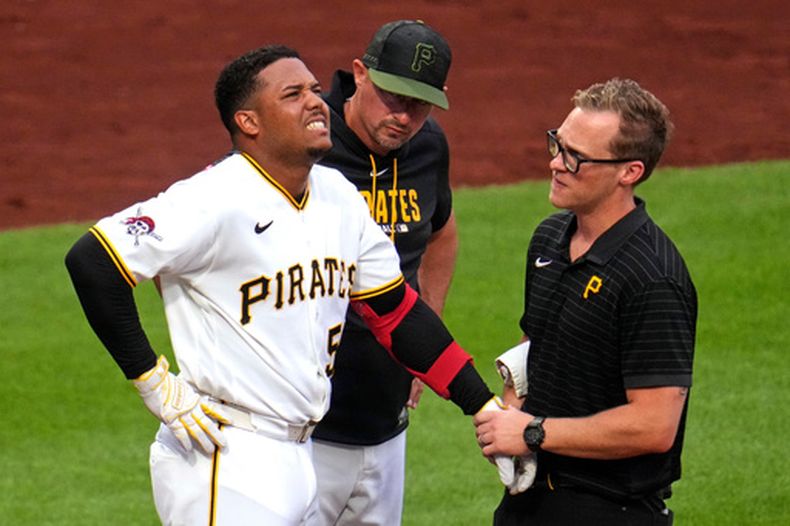 El mánager de los Piratas de Pittsburgh Don Kelly con el pelotero dominicano Esmerlyn Valdez mientras es examinado por el médico tras golpeado por una bola de Merrill Kelly de los Diamondbacks de Arizona el lunes 27 de julio del 2026. (AP Foto/Gene J. Puskar)