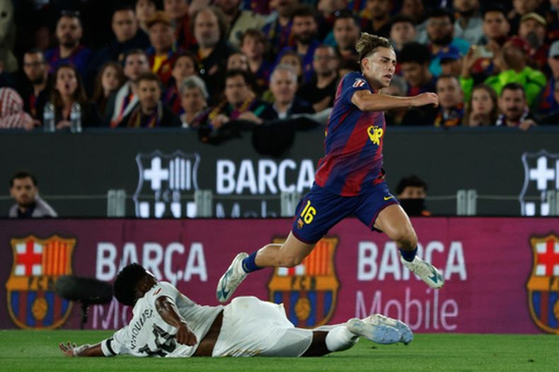 Aurelien Tchouameni del Real Madrid se barre ante el avance de Fermín López del Barcelona en el partido de la Liga de España, el domingo 10 de mayo de 2026, en Barcelona. (AP Foto/Joan Monfort)